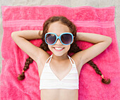 Hispanic girl laying on beach in bikini and sunglasses, Rockaway Beach, NY