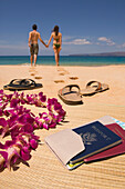 Couple walking away from passport and sandals on beach, Maui, HI