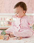 Mixed race baby girl playing with alphabet blocks, Jersey City, NJ