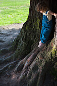 Mixed race girl leaning on tree trunks, Palo Alto, CA