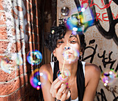 Mixed race woman blowing bubbles