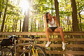 Hispanic cyclist sitting on bridge railing, Virginia Beach, VA