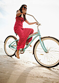 Hispanic woman riding retro bicycle on beach, Dana Point, CA, USA