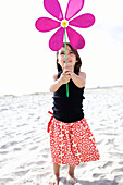 Hispanic girl playing with toy flower on beach, San Diego, CA, USA