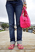 Hispanic woman on boardwalk in flipflops and carrying purse, Laguna Beach, CA, USA