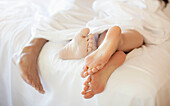 Close up of couple's feet in bed, Stowe, Vermont, USA