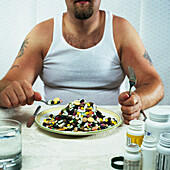 Overweight man eating plate full of pills, Potomac, Maryland, USA