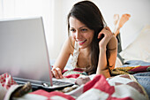 Brazilian woman using laptop in bed, Jersey City, New Jersey, United States