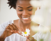 Black woman plucking petals from daisy, Jersey City, New Jersey, USA