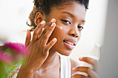Black woman putting on face lotion, Jersey City, New Jersey, USA