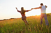 Caucasian couple walking in field holding hands, Olney, Maryland, USA