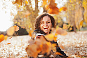 Caucasian woman playing in autumn leaves, Provo, Utah, USA