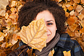 Caucasian woman laying in autumn leaves, Provo, Utah, USA