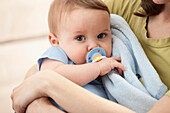 Caucasian baby boy with pacifier in mother's arms, Lehi, Utah, USA
