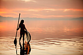 Caucasian woman standing with paddle board at sunset, Salt Lake City, Utah, USA