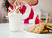 Mixed race girl dunking cookie into milk, Jersey City, New Jersey, USA