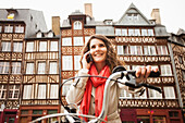 Caucasian woman riding bicycle and talking on cell phone, Rennes, Brittany, France