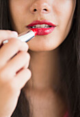 Hispanic teenager putting on lipstick, Jersey City, New Jersey, USA