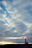 Lighthouse beaming under cloudy sky, Newport, Oregon, USA