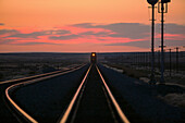 Sunset over train on tracks in rural landscape, Mountain Home, ID, USA