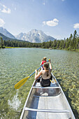 Caucasian mother and daughter paddling canoe on lake, Jackson, Wyoming, USA