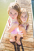 Caucasian girls standing back to back on dock, American Fork, Utah, USA