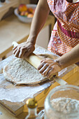 Mixed race woman rolling dough on cutting board, Austin, TX, USA
