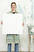 Caucasian painter holding blank canvas in studio, Halifax, Nova Scotia, Canada