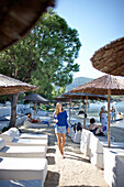 Woman walking along a hotel beach, Chalkidiki, Greece, Model Release for woman in front