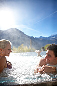 Couple in a hotel outdoor pool, Engstligenalp and Wildstrubel in background, Adelboden, Canton of Bern, Switzerland