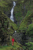 Frau wandert auf dem Souther Upland Way, Grey Mares Tail im Hintergrund, Dumfriesshire, Schottland, Großbritannien