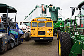 American school bus and new farm vehicles on a parking area before shipping, Bremerhafen, Bremen, Germany