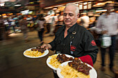 Waiter serving steak and fries, Parilla type restaurant, Mercado del Puerto, Montevideo, Montevideo, Uruguay