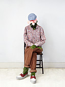 Model of man made of plants sitting on chair