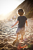 Little boy on sandy beach at sunset