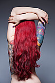 Young woman with long red hair and tattoos, studio shot