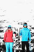 Young people wearing skiwear carrying skis