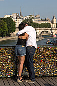 Romantic couple on the pont des arts bridge covered in love padlocks, quay of the louvre, paris (75), france