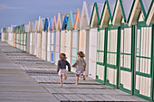 Little girls running near the beach huts of cayeux-sur-mer, somme (80), picardie, france