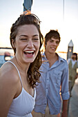 Lachende junge Frau auf Boot, Porträt, mit jungem Mann im Hintergrund
