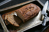 Loaf of Banana Bread with Two Slices and Knife on Tray