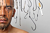 Man Surrounded by Hanging Fish Hooks Looking at Cigarette on Fish Hook, Close-Up
