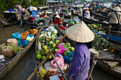 A vietnamese woman with typical conic hat sells vegetables on her boat in the Phung Hiep floating market near Can Tho, Mekong Delta, Vietnam