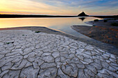 High tide and textures in the mud along the banks of the Couesnon river at sunset with Mont Saint Michel in the background, Mont Saint Michel, Brittany, France