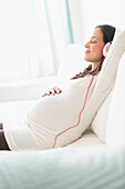 Pregnant Hispanic woman listening to headphones, Jersey City, NJ, USA