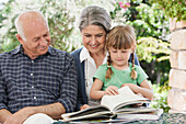 Grandparents and granddaughter reading outdoors, Cape Town, Western Cape, South Africa