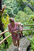 Caucasian mother carrying baby up steps in jungle landscape, Ubud, Bali, Indonesia