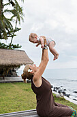 Caucasian mother and baby playing outdoors, Candidasa, Bali, Indonesia