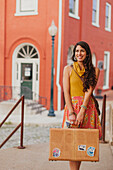 Mixed race woman carrying suitcase on city street, Charlottesville, VA, USA