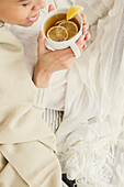 Black woman drinking cup of tea with lemon, Jersey City, New Jersey, USA